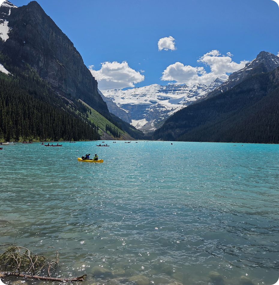 Turquoise lake, snowy mountains, and evergreen trees.